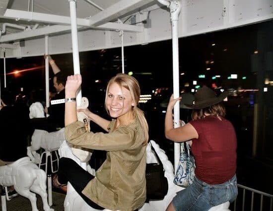 a woman is riding a carousel at night.