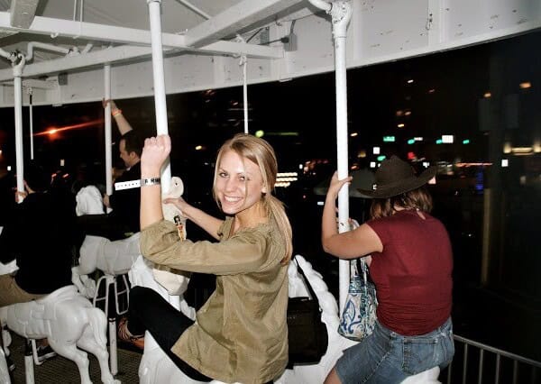 a woman is riding a carousel at night.