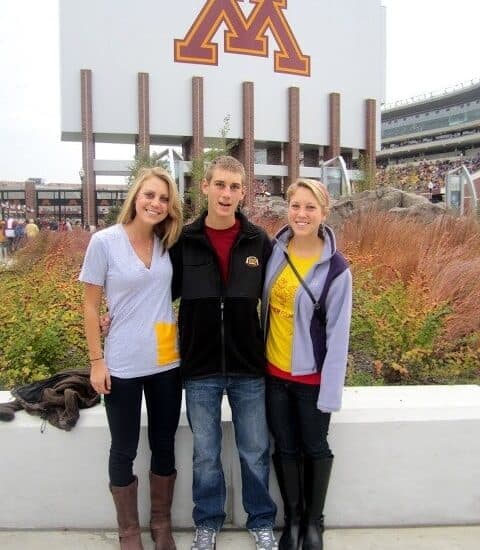 three people standing in front of the minnesota golden gophers stadium.