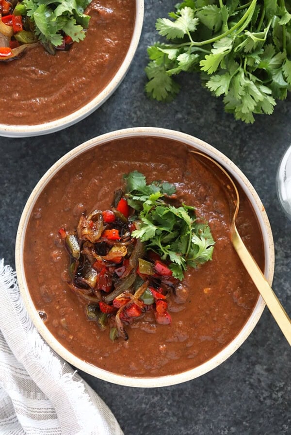Two bowls of black bean soup on a table.