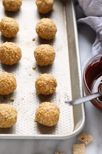 Granola bites on a baking sheet with a bowl of dipping sauce.