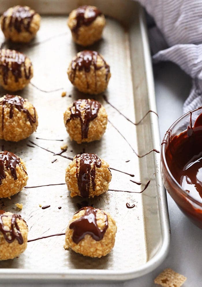 A tray of chocolate covered peanut butter balls on a baking sheet.