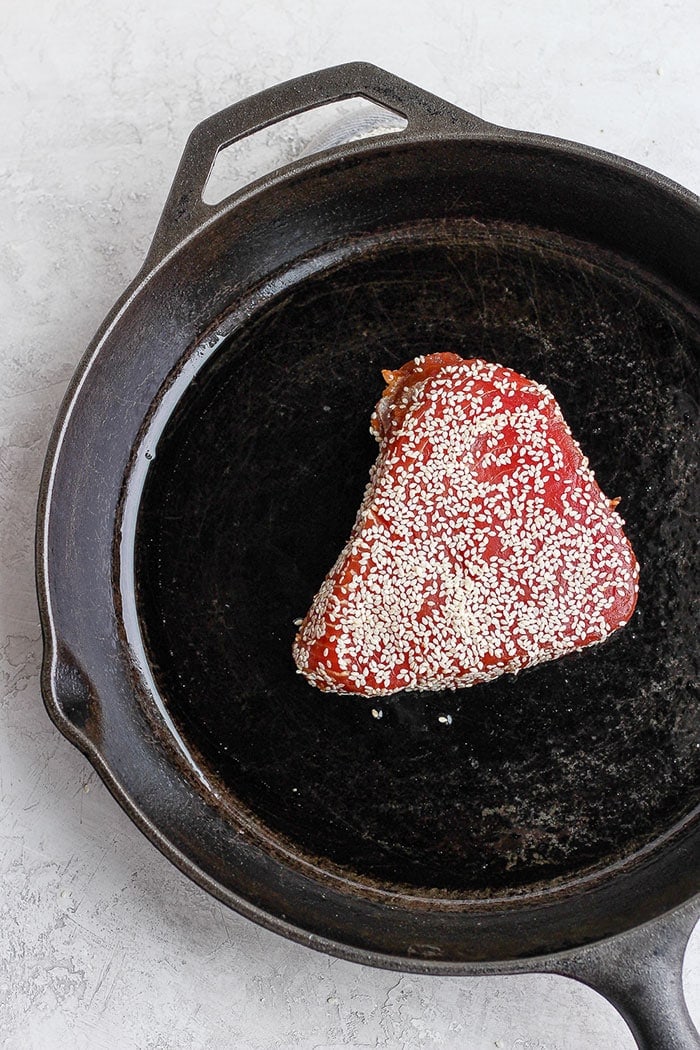 ahi tuna being seared in a cast iron skillet.