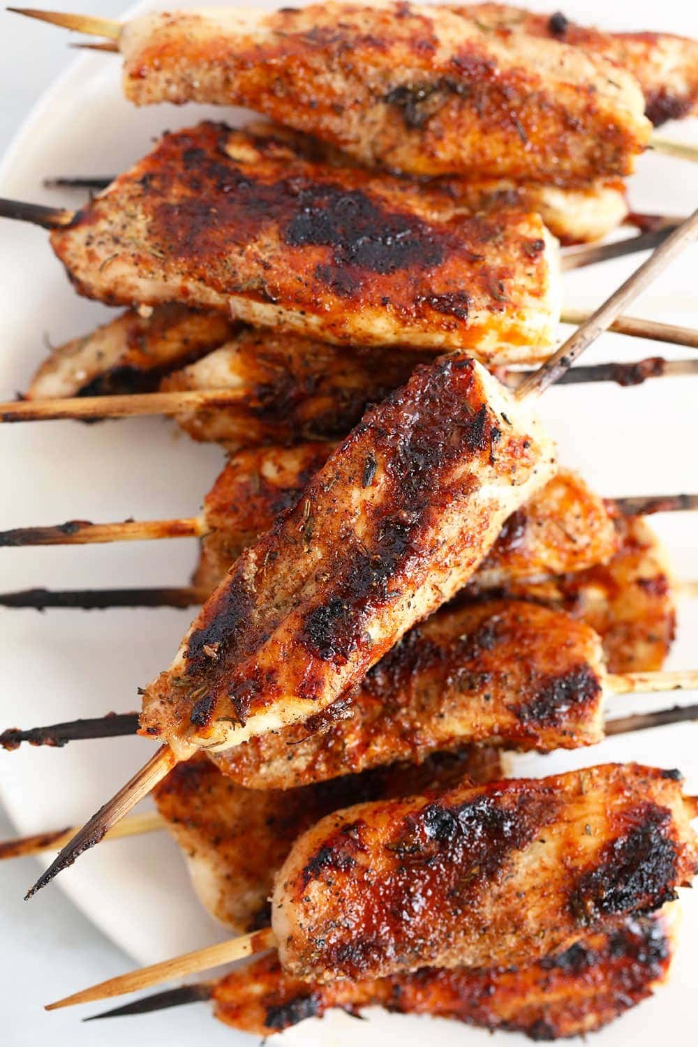 These BBQ Chicken Skewers are the perfect summer meal! Grab some skewers, BBQ sauce, and your favorite BBQ side dish and let's grill! Grilled chicken skewers on a plate.