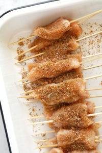 Chicken skewers arranged in a baking dish.