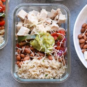 Save your money and make your own affordable Copycat Chipotle Chicken Burrito Bowls at home! These healthy chicken burrito bowls are made just like the real thing made with baked chicken, cilantro lime brown rice, beans, and fajita veggies, and your favorite toppings!