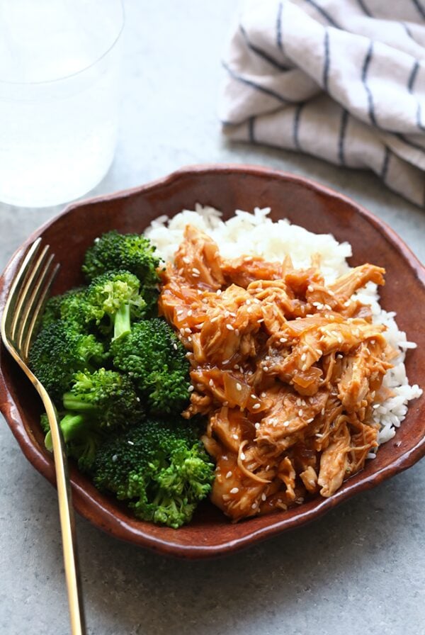 A brown bowl with Crockpot Sesame Chicken and rice.