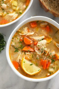 two bowls of chicken soup on a marble table.