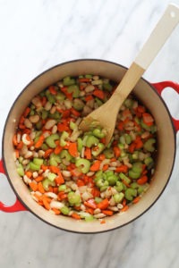 A hearty chicken soup packed with nutritious vegetables, quinoa, and beans, served on a stylish marble countertop.