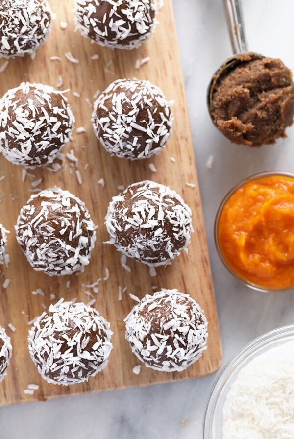 chocolate coconut energy balls garnished with pumpkin seeds on a cutting board.