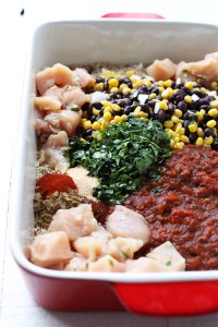 a chicken casserole with beans, corn and other ingredients in a red baking dish.