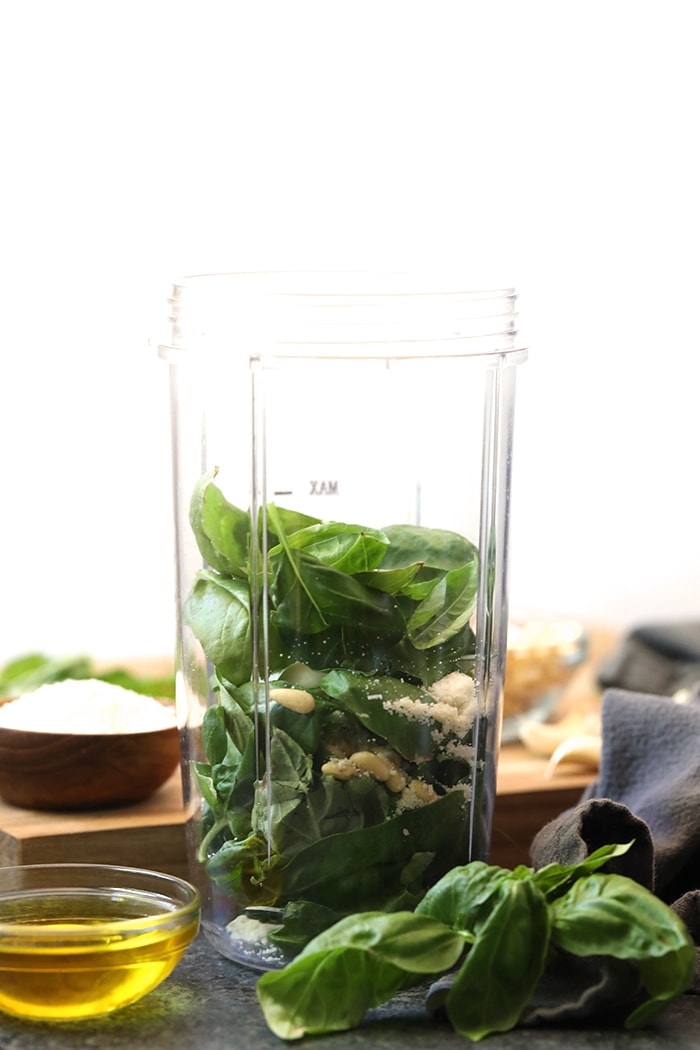 Put all that garden-fresh basil to good use with this healthy pesto recipe that seriously only takes 5 minutes to make. Whip up a batch for your next seasonal dish, or triple a batch and keep in your freezer to have on hand whenever you need it! Making healthy pesto has never been easier. Basil and pine nuts in a food processor.