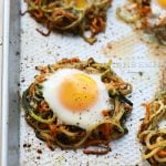 Spiralized zucchini noodles with eggs and carrots on a baking sheet.