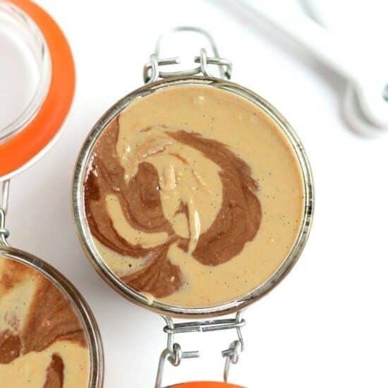 Three jars of peanut butter and cashew butter with a spoon next to them.