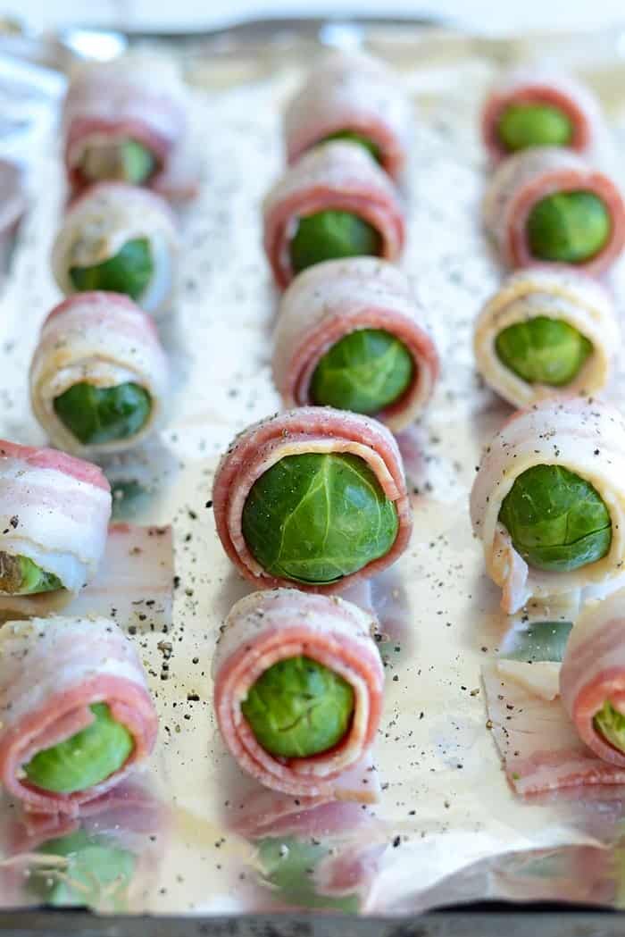 Bacon wrapped brussel sprouts on a baking sheet ready to be cooked.