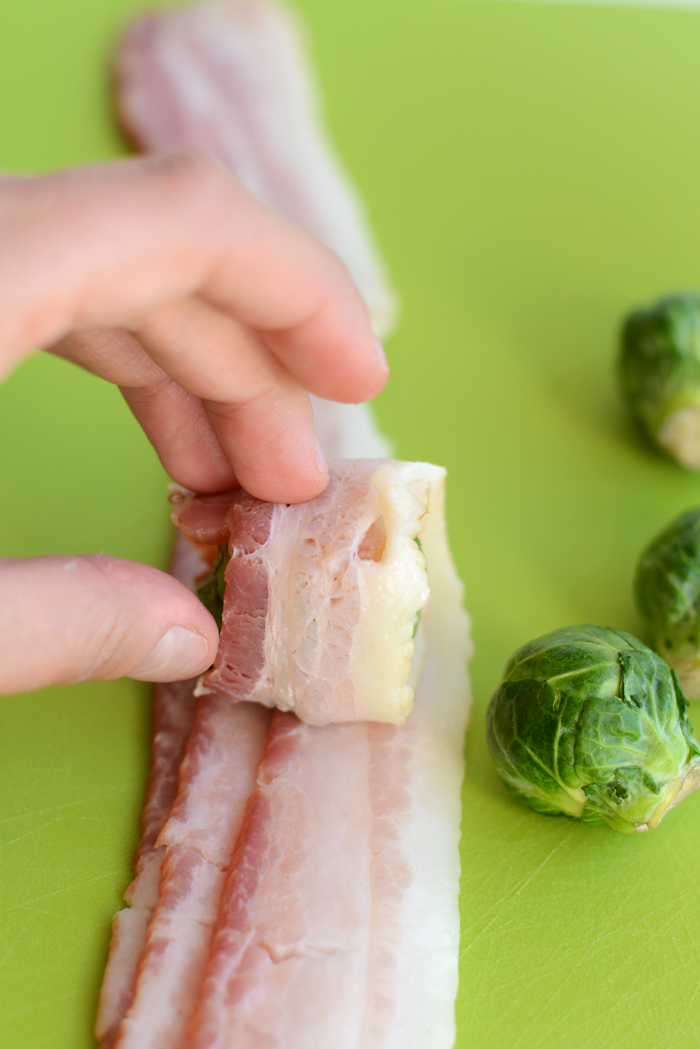Wrapping a brussel sprout with one slice of raw bacon. 