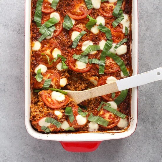 A red baking dish with a tomato and cheese chicken quinoa bake.