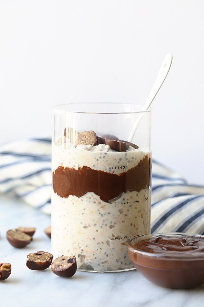 a glass of overnight chocolate oatmeal with a spoon and chocolate chips.