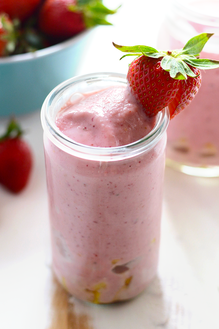 strawberry pineapple smoothie with strawberry on rim