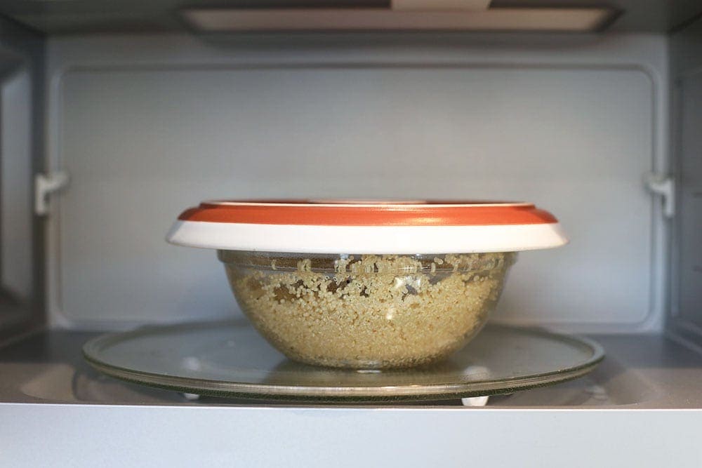 quinoa in a microwave-safe bowl with a lid placed in the microwave