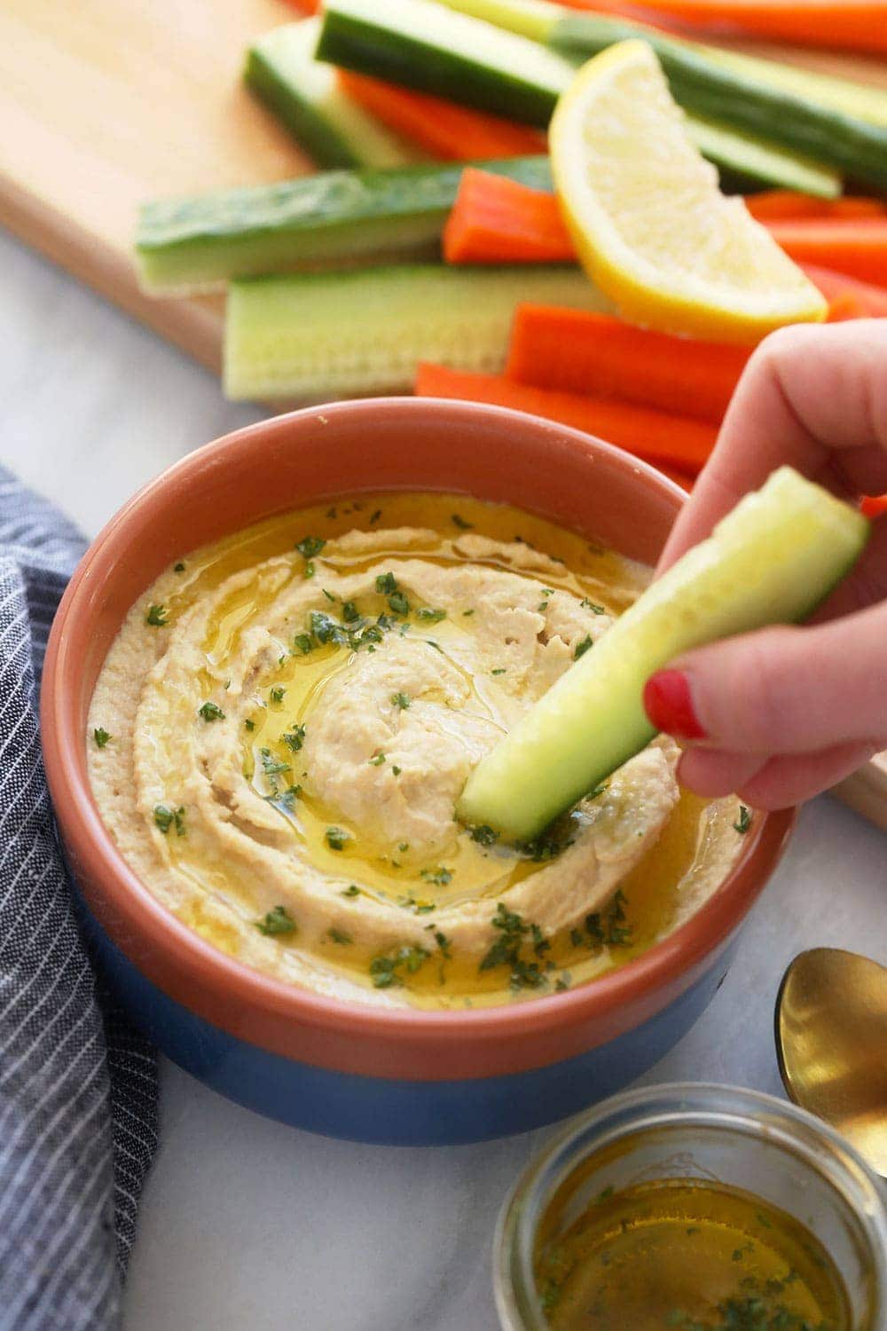 lemon garlic hummus in a bowl with a veggie dipped in it
