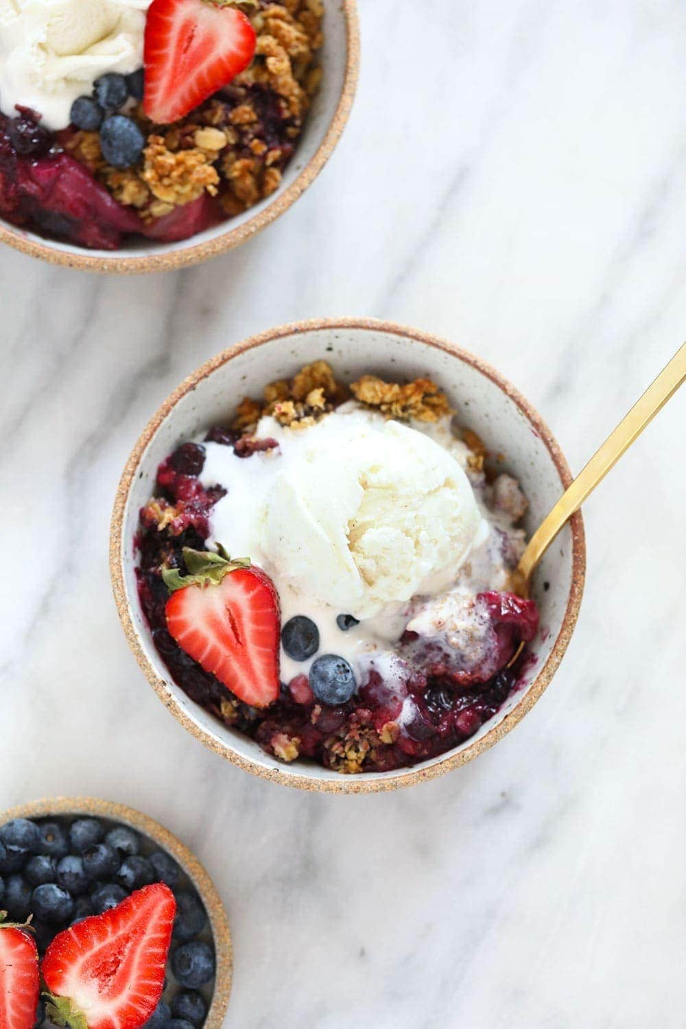 berry crisp in bowl with ice cream on top