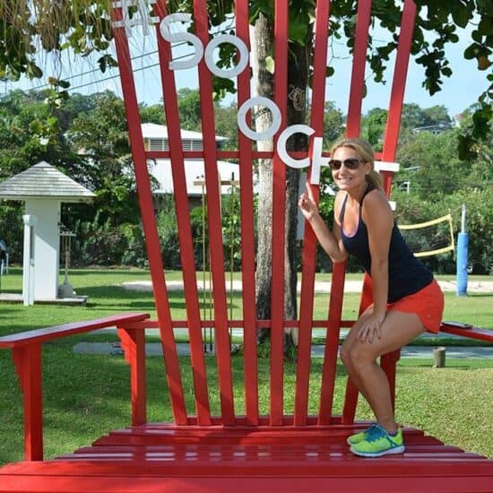 A woman posing in front of a large red chair at Sandals Ochi Beach Resort.