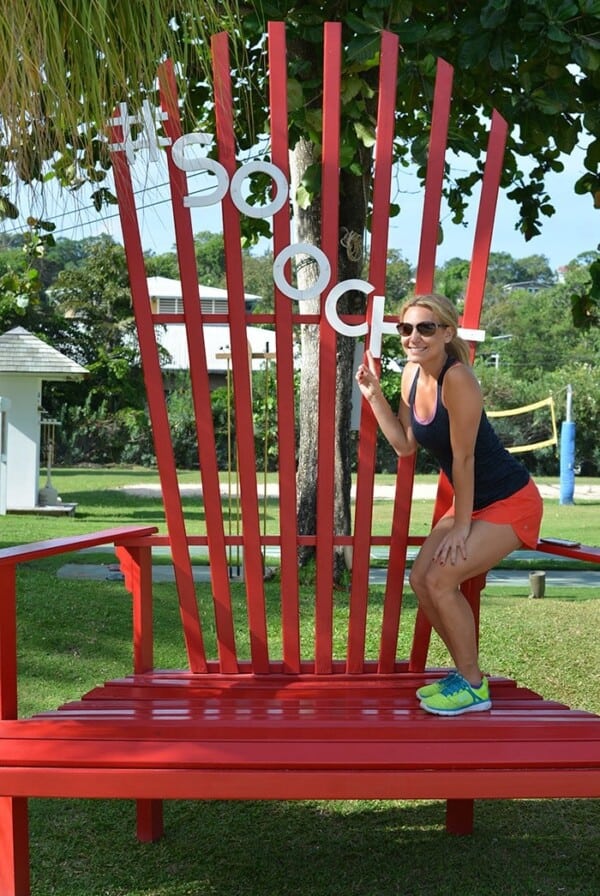 A woman lounging on a large red adirondack chair at Sandals Ochi Beach Resort.