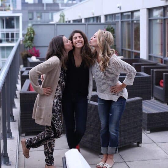 Three women posing for a photo on a Toronto rooftop.