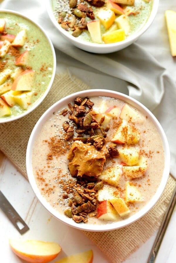 Three bowls of oatmeal with apples and a sprinkle of granola.