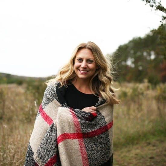 a woman in a plaid blanket standing in a field during November 2015.