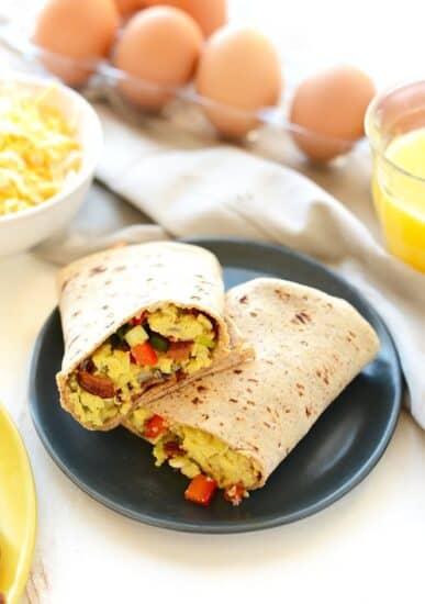A plate of scrambled eggs and vegetables in a breakfast burrito.