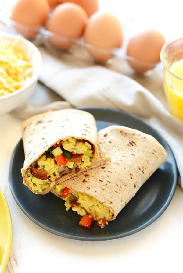 A plate of scrambled eggs and vegetables in a breakfast burrito.