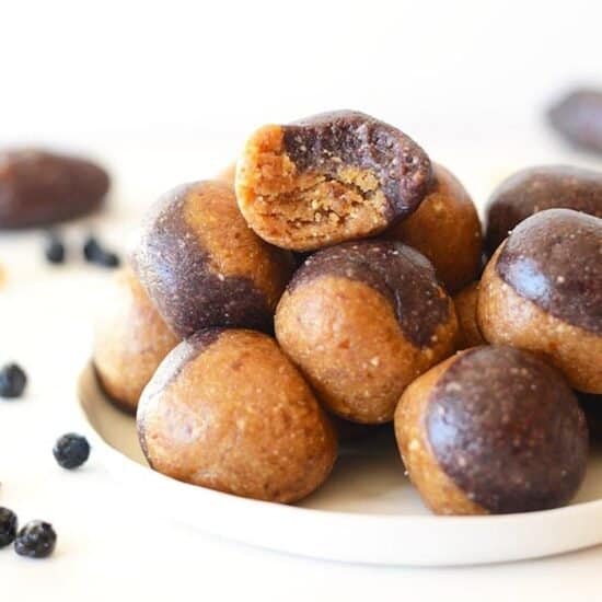 a plate of blueberry-filled energy balls coated in chocolate peanut butter.