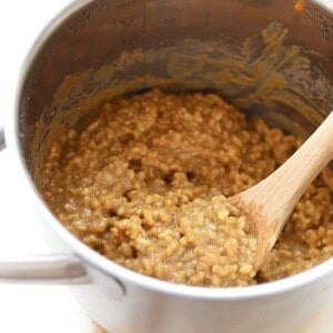 Oatmeal cooked in a pan with a wooden spoon.