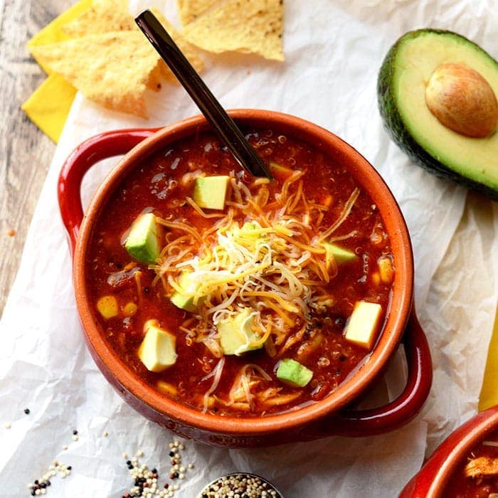 chicken enchilada soup in a bowl topped with avocado and shredded cheese