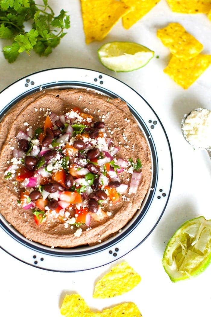 mexican black bean hummus in a bowl topped with cotija cheese and diced tomatoes