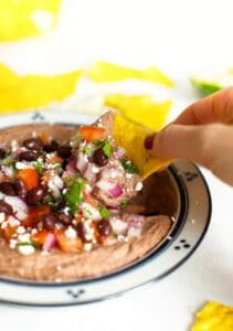 mexican black bean hummus in a bowl with a chip dipped in it