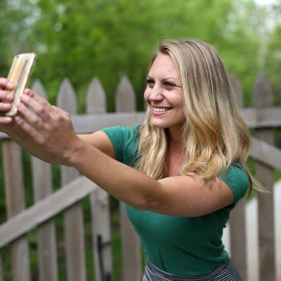 a woman taking a selfie in front of a fence.