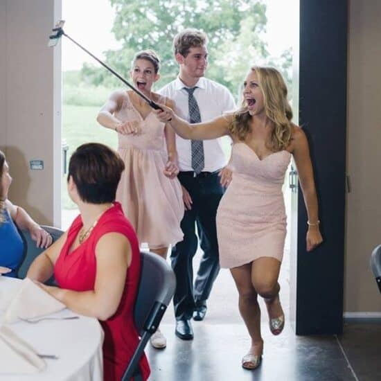 a group of people holding a selfie stick at a wedding.