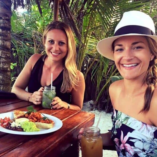 Two women sitting at a table with plates of Mexican food in Tulum.