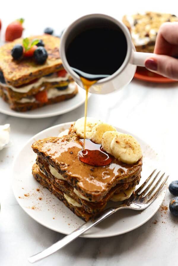 stuffed french toast on plate with banana slices and syrup being poured over