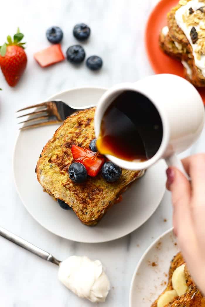 Stuffed french toast on a plate with maple syrup being poured over it. 