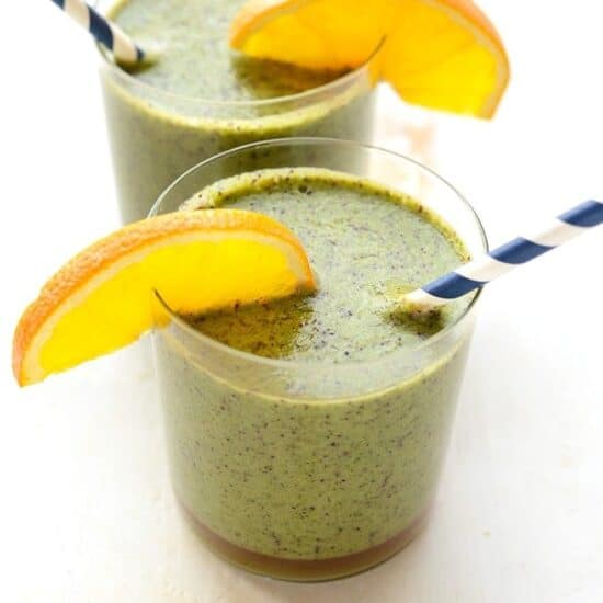 two glasses of green smoothie with blueberry and spinach.