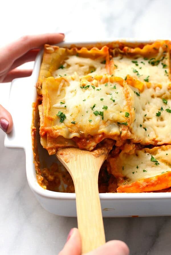 Sweet Potato Lasagna in a white baking dish with a wooden spoon.
