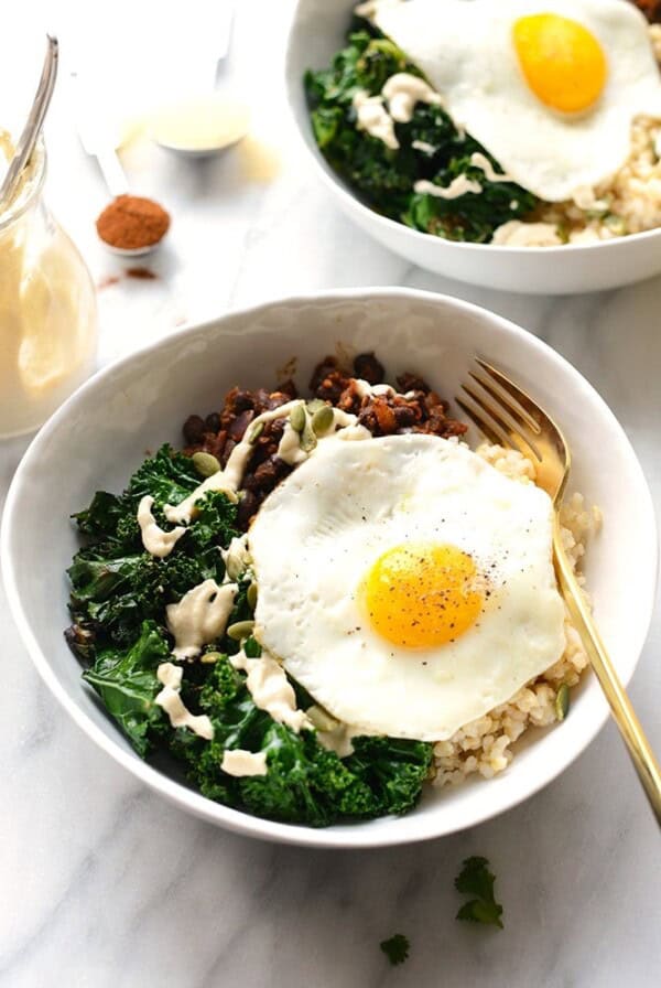 A black bean breakfast bowl topped with an egg, kale, and quinoa.
