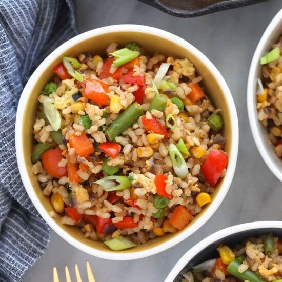 Three bowls of fried rice with vegetables.