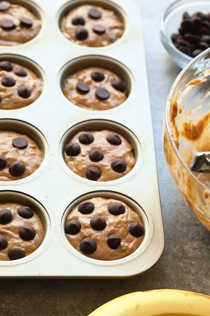 Banana chocolate chip muffin batter in a muffin tin, ready to be baked.