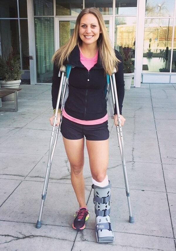 a woman standing in front of a building with crutches.