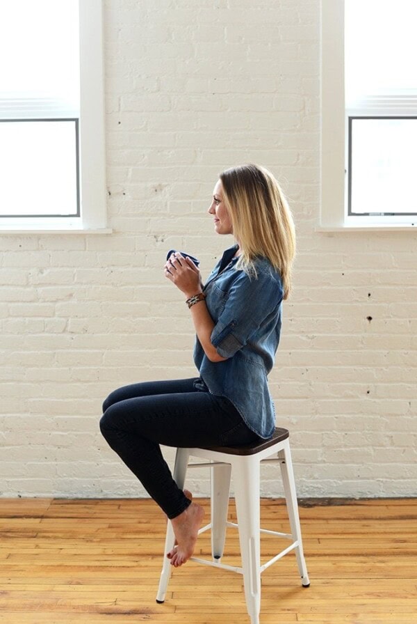 a woman enjoying coffee on a stool.